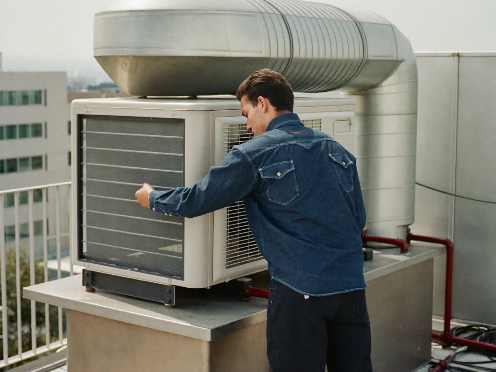 Técnico dando mantenimiento a una unidad de aire acondicionado en un edificio de oficinas